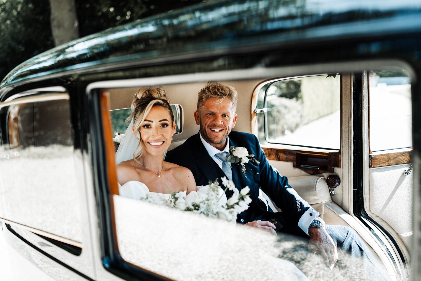 Bride and groom smiling in a vintage wedding car, Cambridgeshire wedding photography by RZ Photography & Film